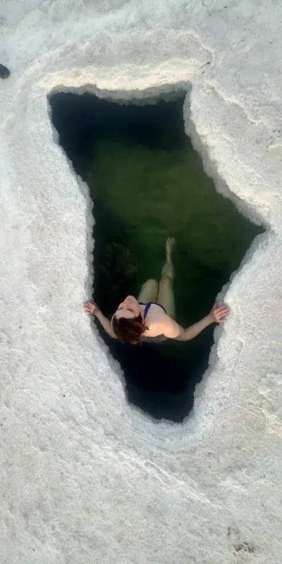 Traveller floating in a salt-rich mineral pool in the Danakil Depression